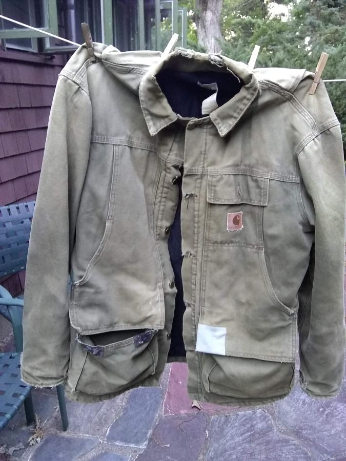 Carhart jacket with many rips and holes hanging on closeline