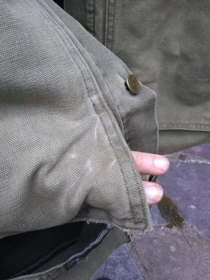 hole (with finger showing through) in pocket of jacket