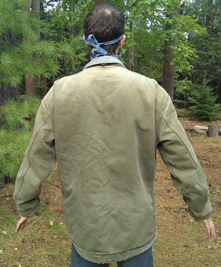 back view of patched Carhartt Jacket worn by man in the woods