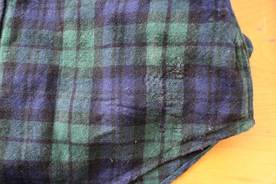 closeup of bottom side of black watch shirt showing some close to invisible mending