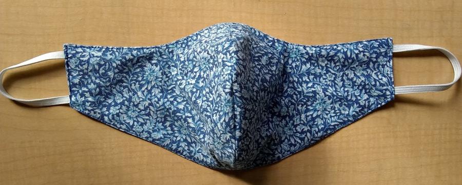 fitted facemark in blue flower print with elastic ear loops on wooden background