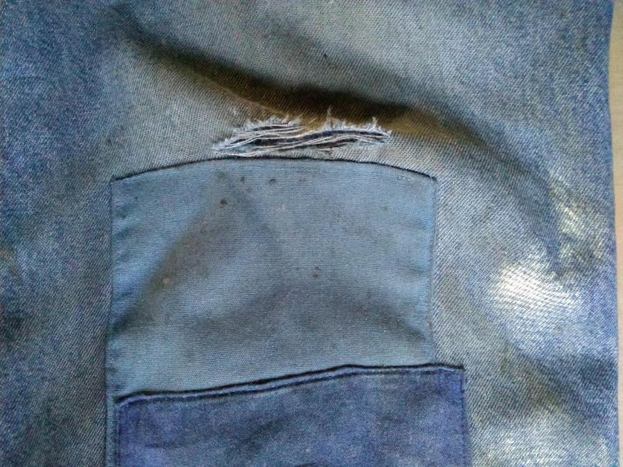closeup of patched blue jeans with a new hole