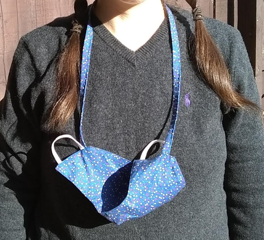 woman's toros with cloth face mask hanging around neck via cloth neck cord. mask has elastic ear loops