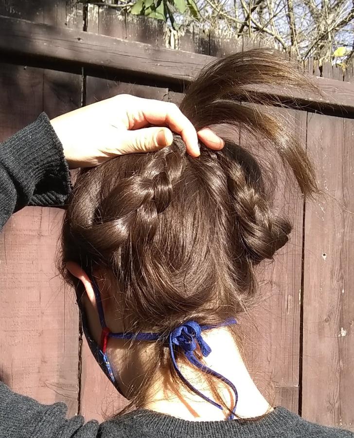 back view of woman's head with braids held up to reveal ties of face mask around ear and tying at nape of neck