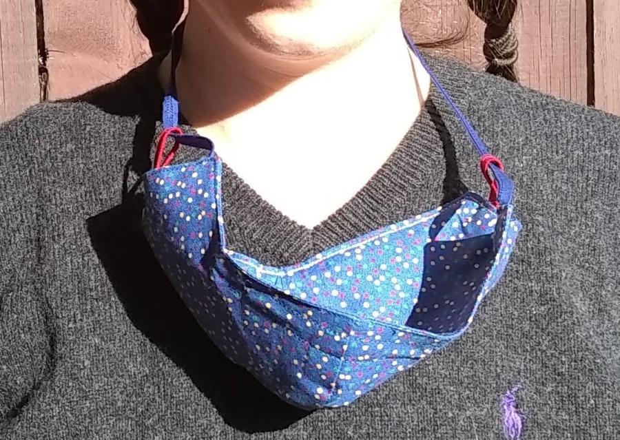 neck and shoulders of woman with cloth face mask hanging around neck by cloth ties