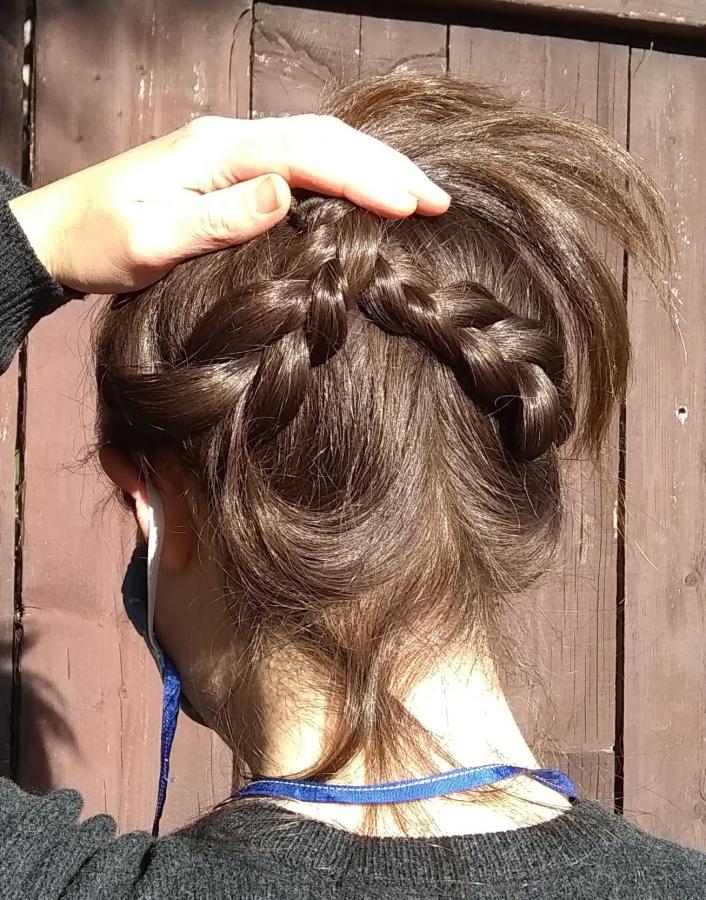 back view of woman's head with braids held up - can see elastic around ears and neck cord of mask