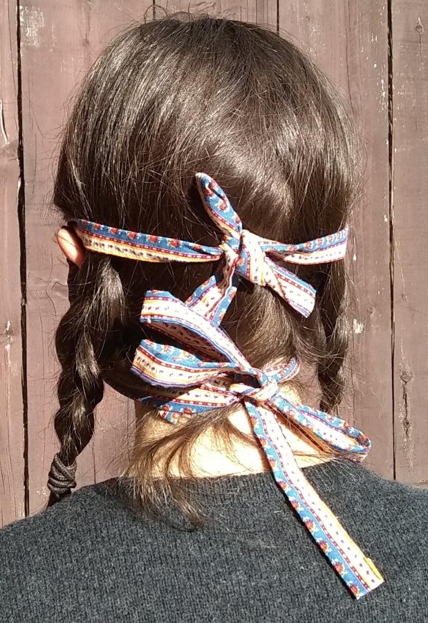 back view of woman wearing cloth tied face mask with ties knotted in bows just about ears and around neck