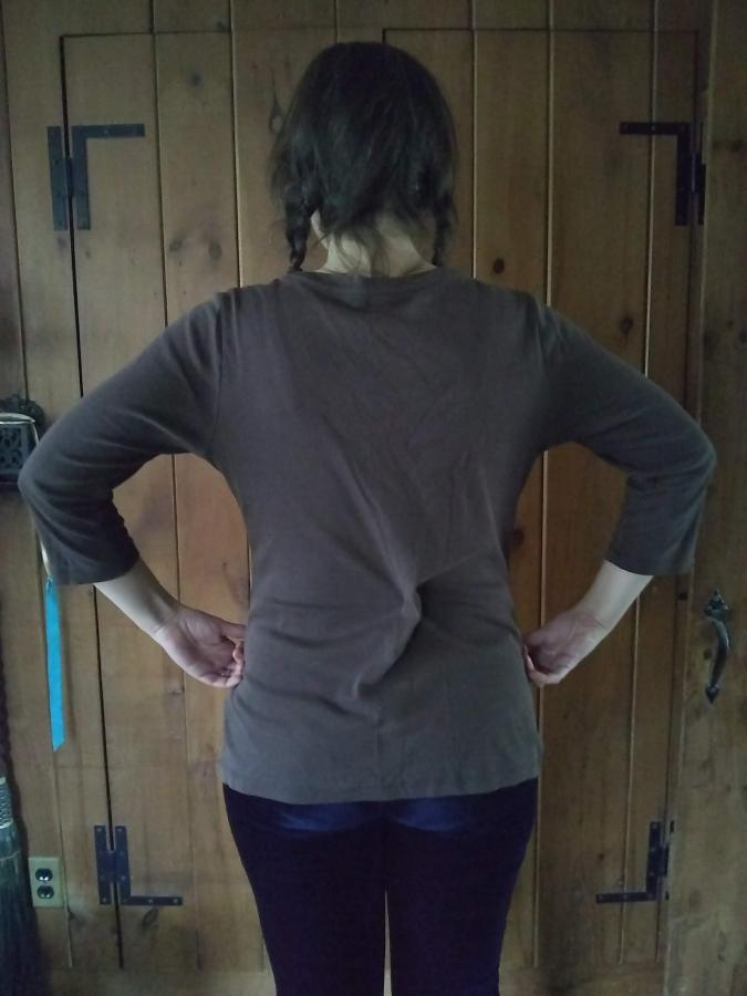 back view of woman in brown shirt with shaped seams and safety pin to narrow waist