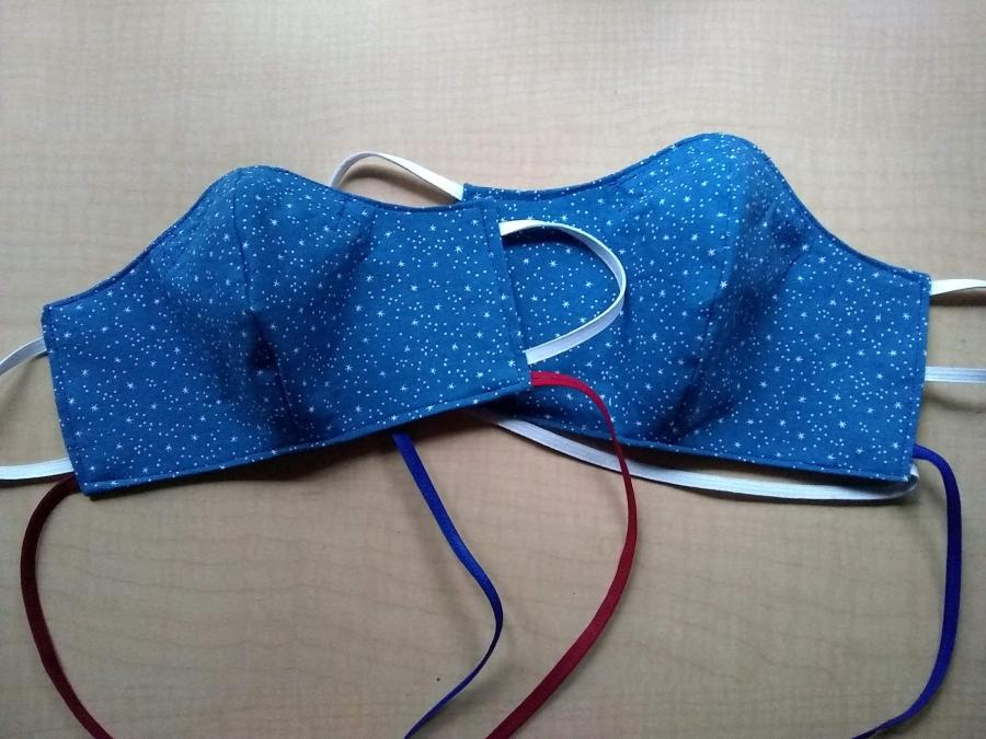 Two fitted masks, in blue star print, with elastic ear loops and neck cords. One mask is slightly smaller than the other. 