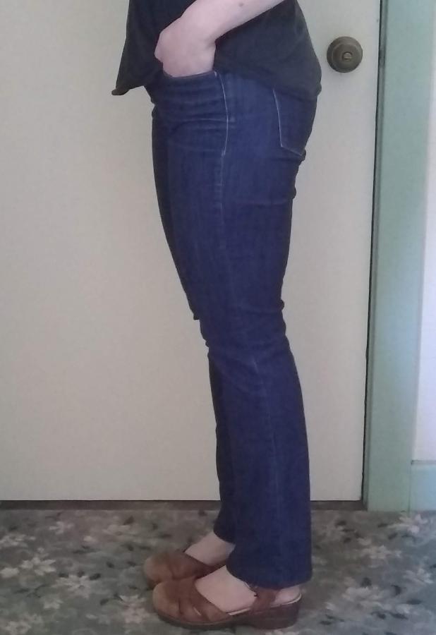 Side view of woman wearing dark very narrow bootcut jeans with correct hem over brown leather shoes