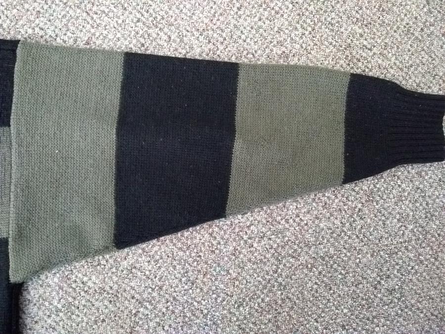 back view of sleeve of olive and black sweater, mended