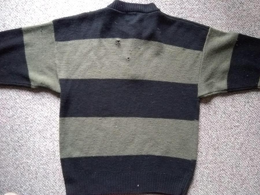 back view of bulky wide striped olive and black sweater with visible holes