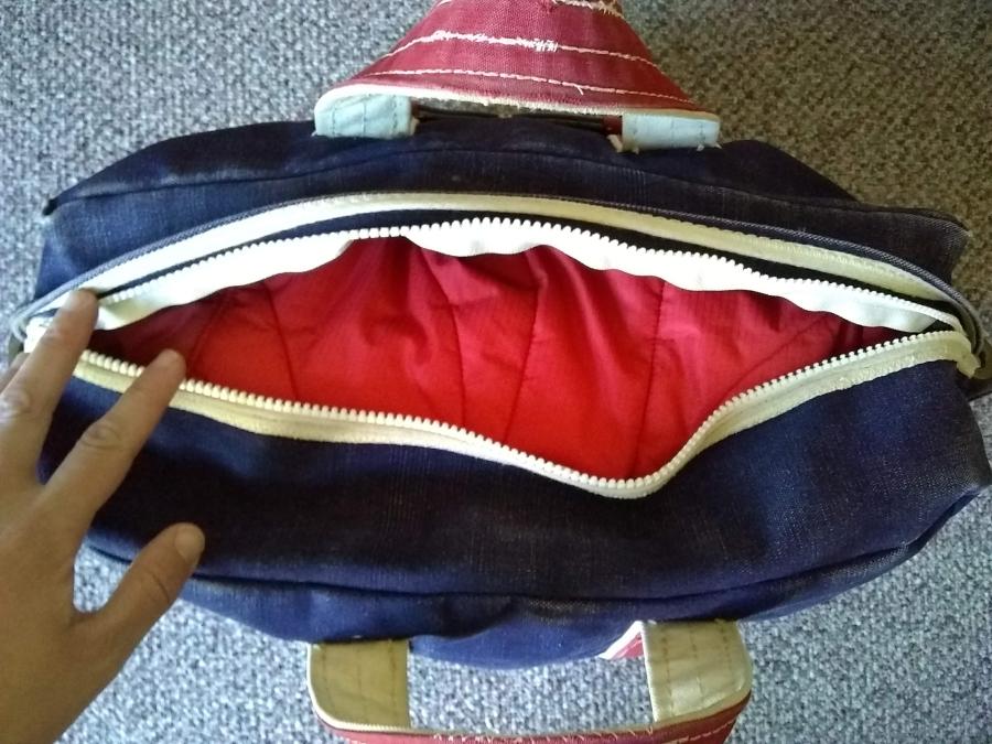 blue tote bag with red handles and replaced zipper, open, with red jacket inside