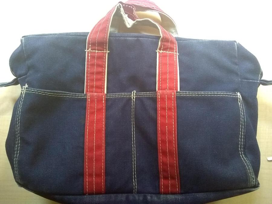 blue tote bag with red handles, front view showing that handle seams have started to fall apart