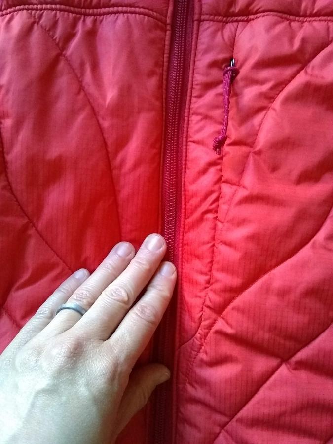 closeup of red winter jacket with replaced zipper, zipped up