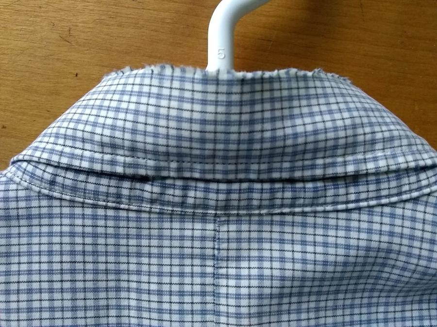 back view of collar of white/blue plaid shirt showing worn fabric at the collar fold
