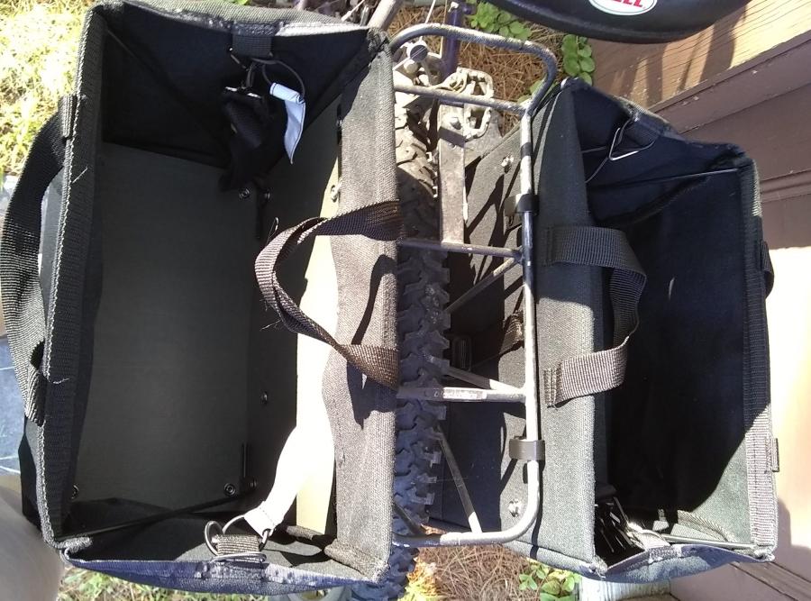 Black bike panniers with open tops mounted on rear rack of bike