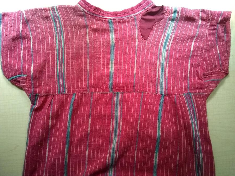 back view of top of red woven dress, with visible red interior patch at the right shoulder