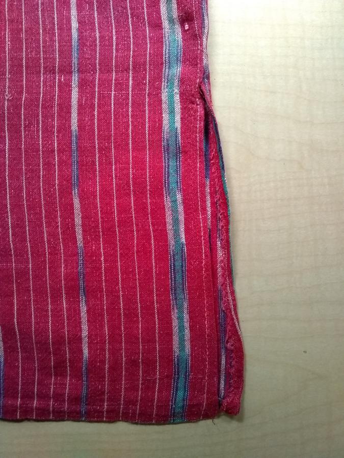 detail of side slit at bottom of red woven dress