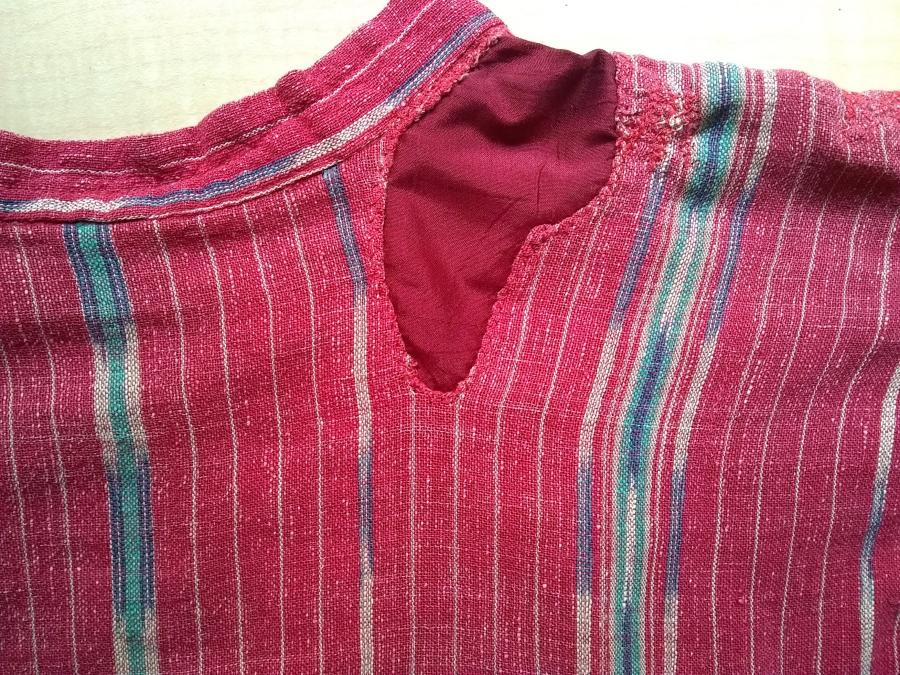 closeup view of visible patch and reinforcing stitching at top back bodice of red woven dress