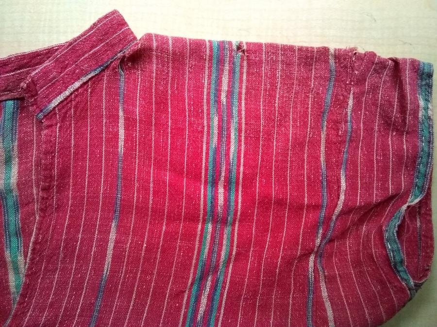 red woven dress, top of bodice, right side, showing worn fabric