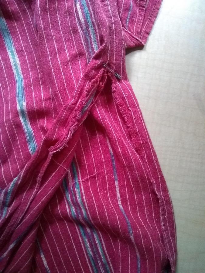 closeup of bottom of red woven dress showing ripped side seam