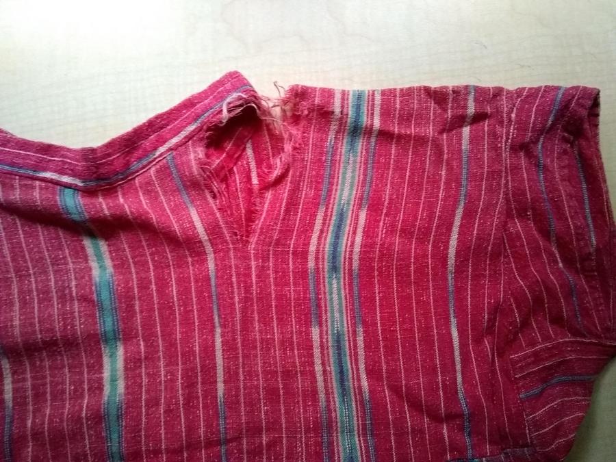neck/shoulder area of red woven dress with large rip at neck/shoulder