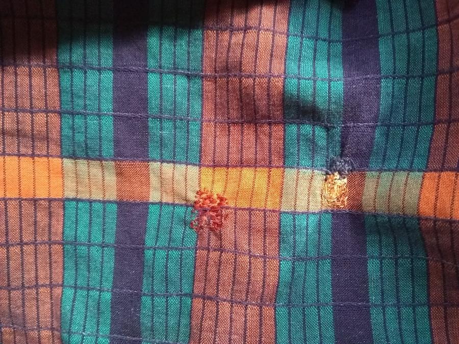 closeup of plaidish fabric with an orange darn on the left and a yellow/navy darn on the right