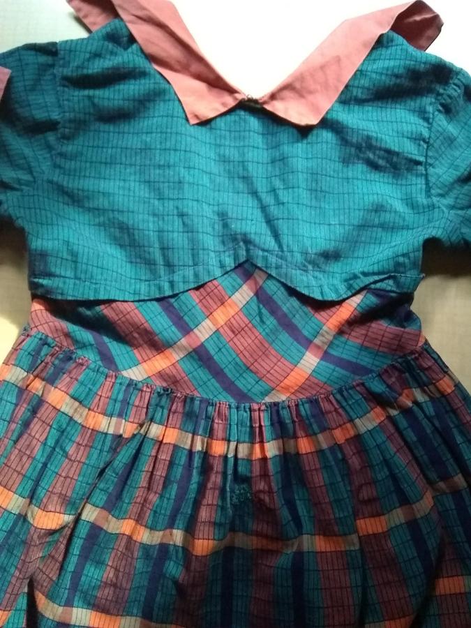 most of a child's plaidish dress, with barely visible darn (green/orange) in the middle top of the skirt