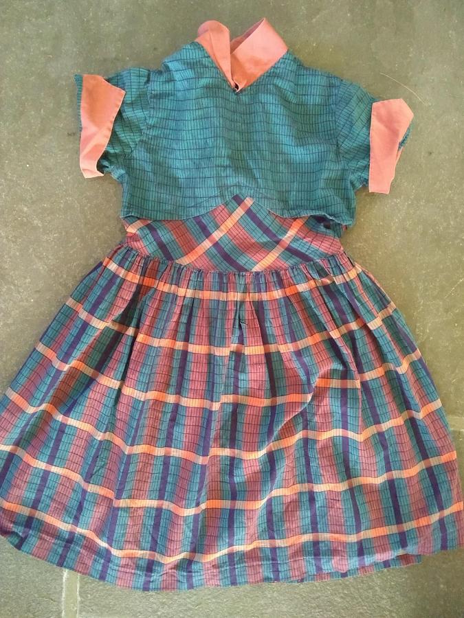 Child's dress with plaidish skirt. Almost invisible rip in the top of the skirt part of the dress, in the middle between two yellow horizontal stripes.