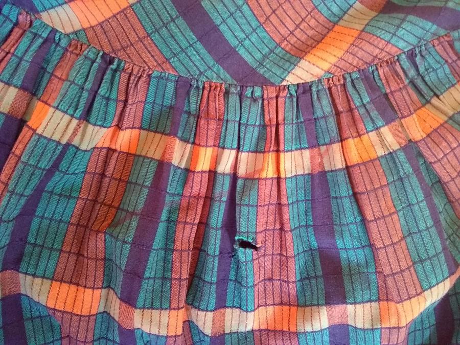 closeup of child's plaidish dress showing rip in the fabric