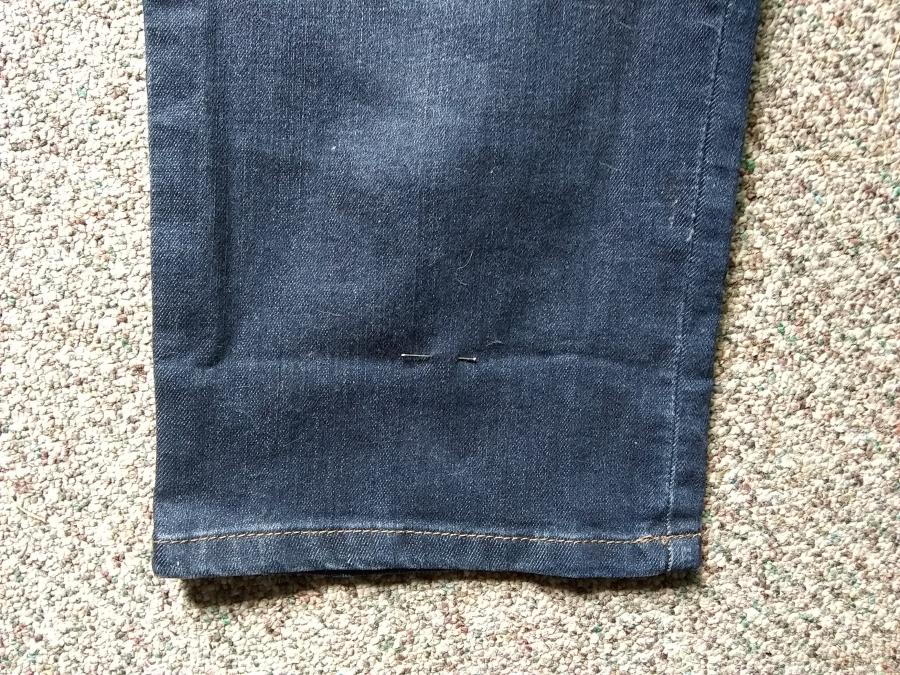 Closeup of bottom of jeans with pin marking where to hem