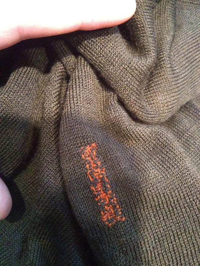 visible persimmon colored and rectangular shaped darn on a brown sweater (closeup of one darn)