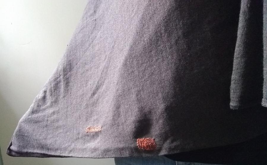 visible persimmon colored and rectangular shaped darns on a brown sweater 