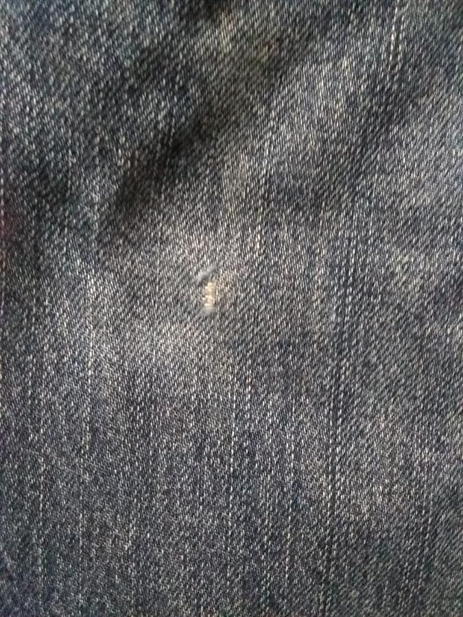 closeup of denim jeans with small area where frayed, white threads are visible