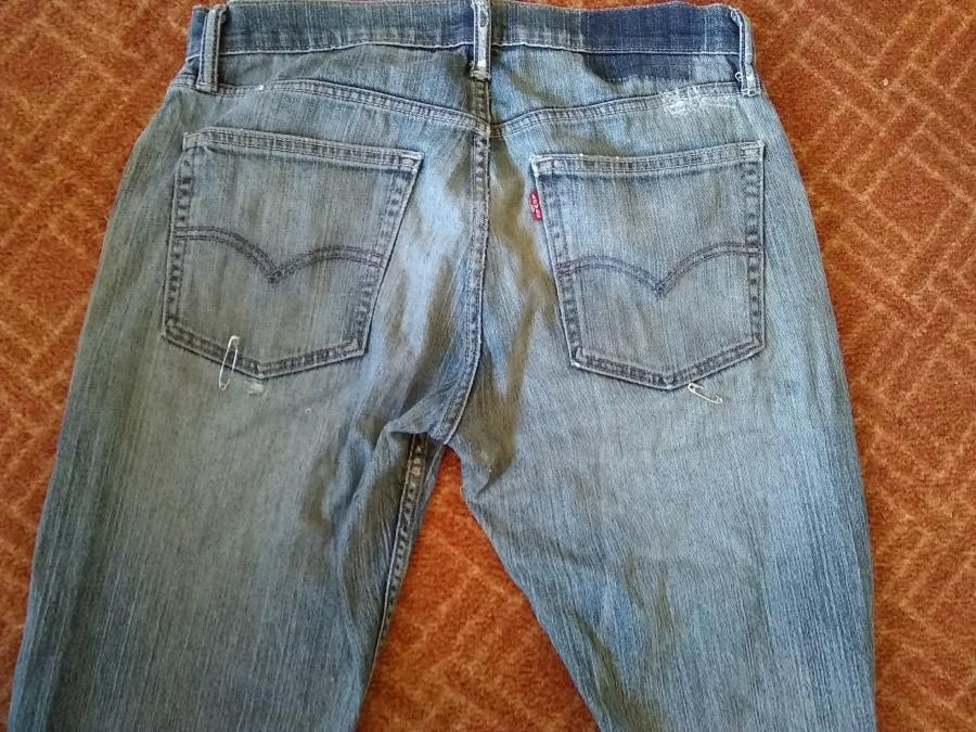 back view of back top of jeans, with worn fabric all around visible