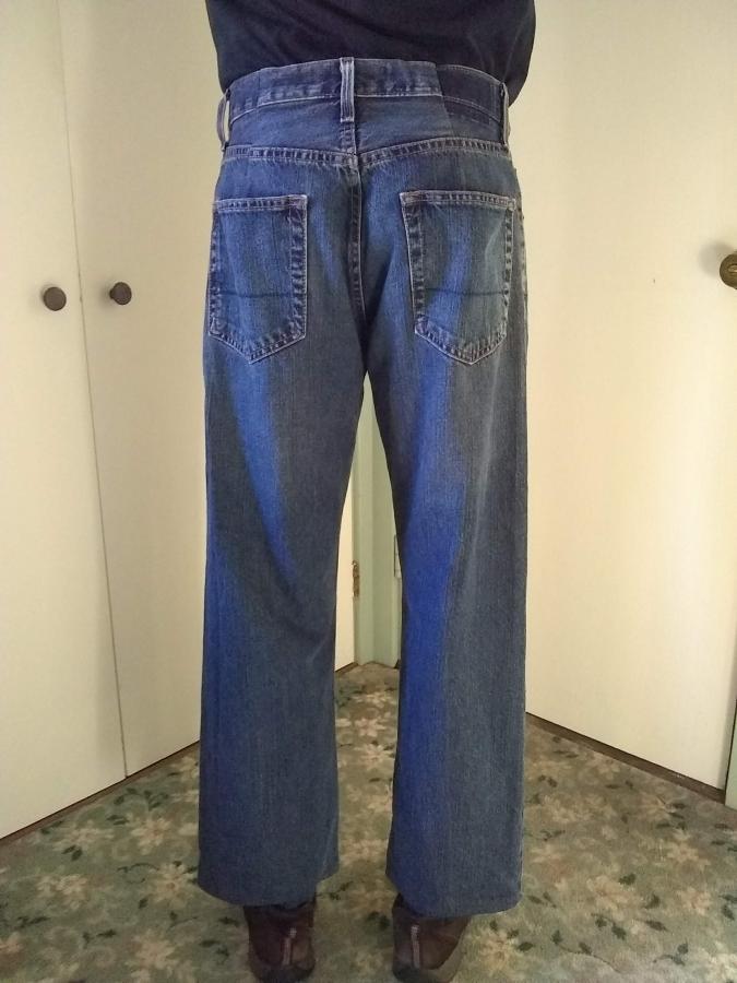 back view of man's legs in blue jeans that are hemmed to fall just above his shoes