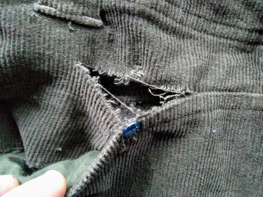 Olive corduroy pants with a rip by pocket rivet