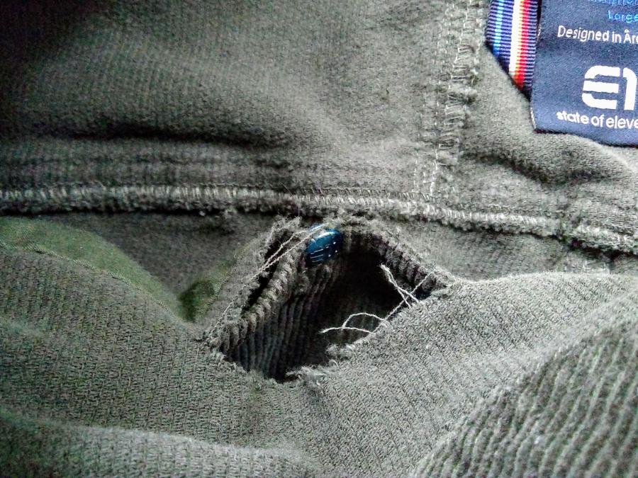 interior of olive corduroy pants, showing wrong side of fabric and rip by pocket rivet