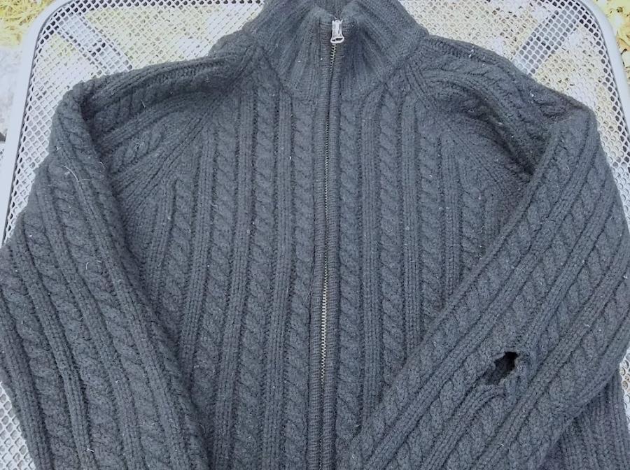 black cabled sweater with hole in the arm