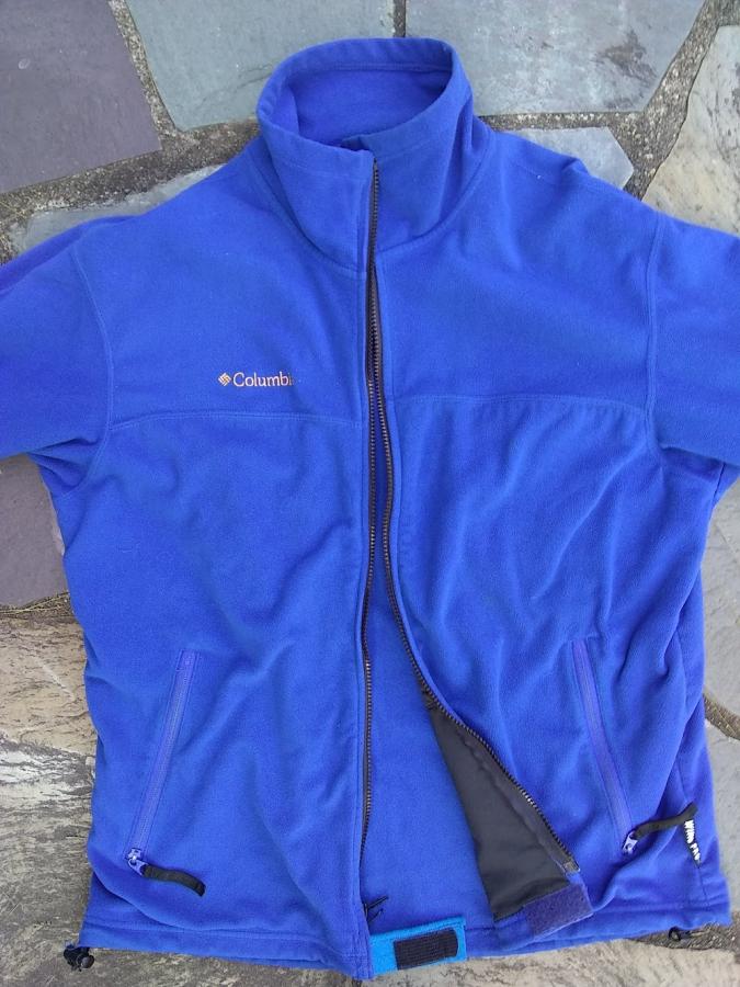 Blue fleece jacket, unzipped, showing blue felt/velcro tab at bottom