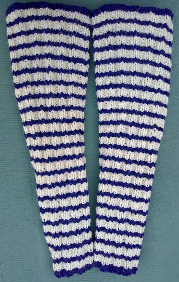 blue and white striped hand-knit  arm warmers on a green background