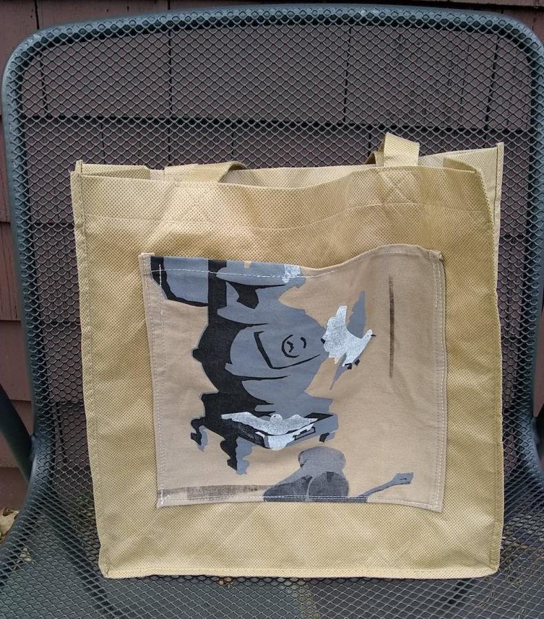beige tote bag with woodstove and bird silkscreen patch sewed to front