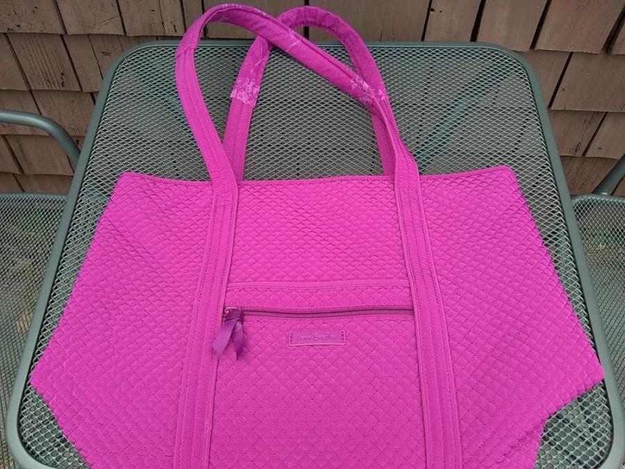 Pink tote bag, lying flat on a table, with handles covered by matching floral print fabric