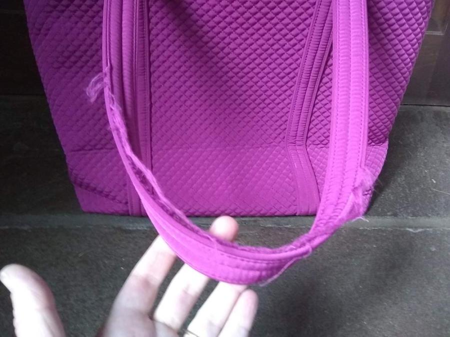 closeup of frayed handle of tote bag, with hand showing the fraying