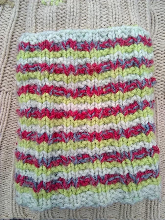 white, green, gray, and red striped knitted patch on beige background