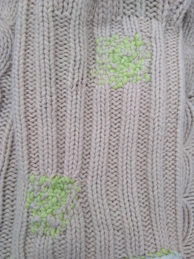 Beige sweater closeup with light green darns