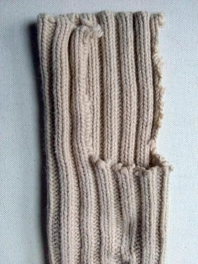 sleeve of beige sweater with large part chopped out of it