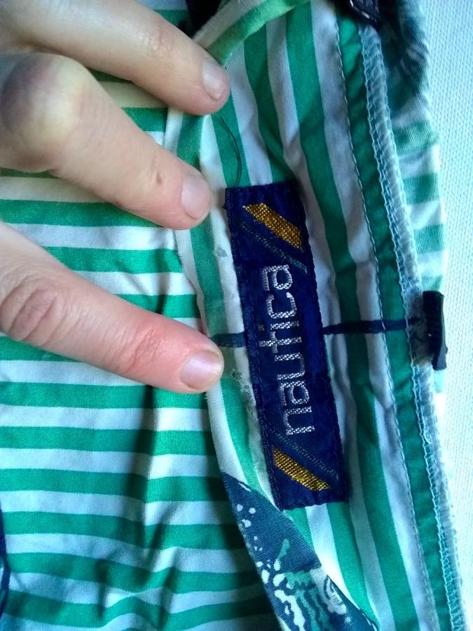 closeup of hand holding inside collar of Nautica brand (label visible) green and white striped bathrobe, showing holes and frayed areas