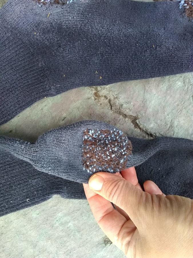 hand showing black sock with blue and brown darn on the heel